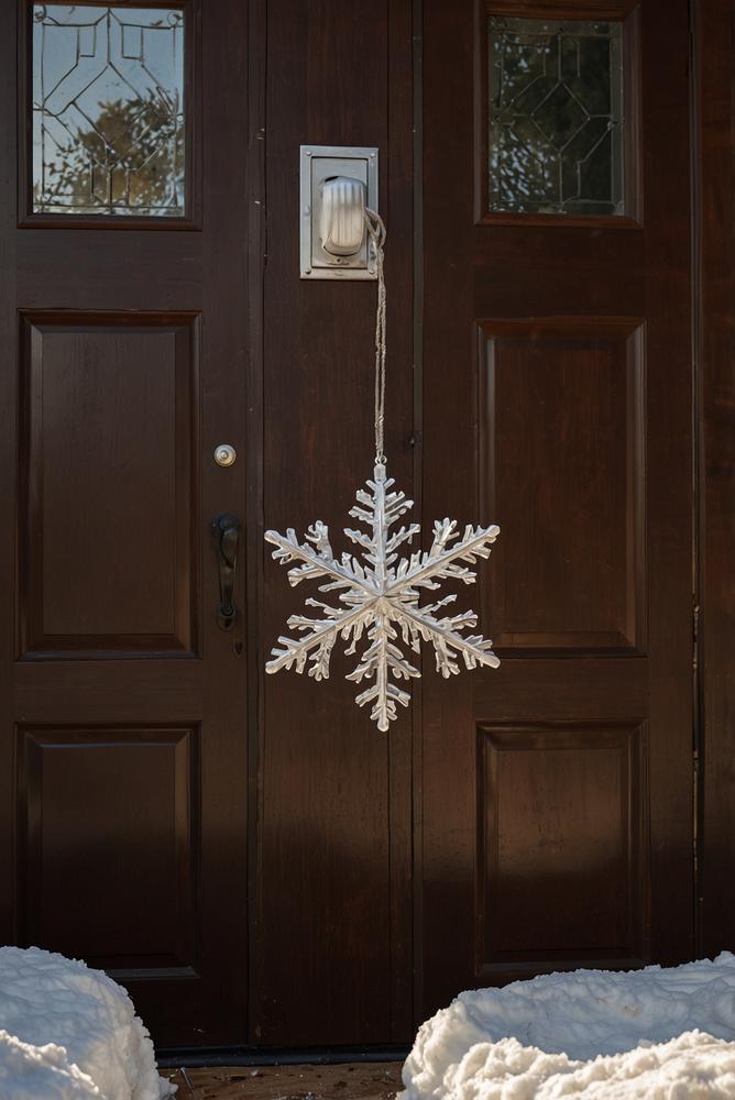 Winterliche Haustür mit DIY-Schneeflocken am Türgriff in hellem Licht